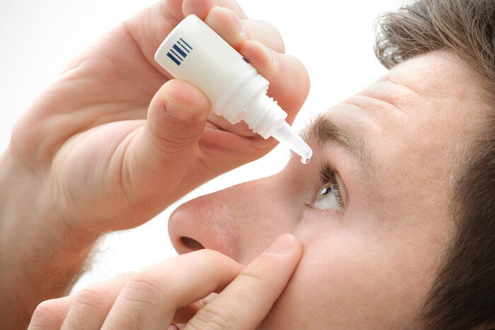 Man putting drops in his eyes