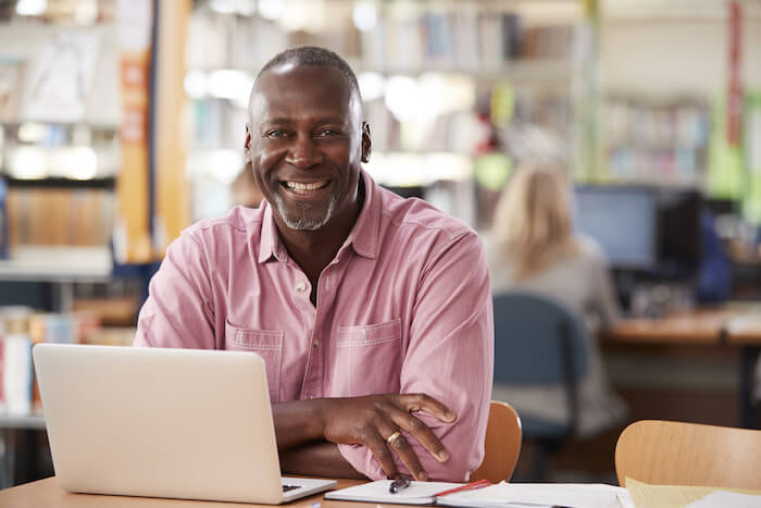 Middle-aged man smiling in front of laptop